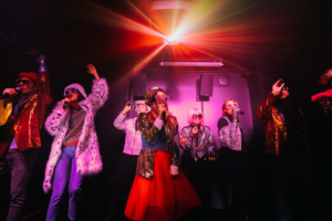 groupe d'amis qui chantent, sur la scène immersive de l'expérience, avec un micro à la main.